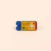 A vintage enamel lapel pin depicting an adventure awaits theme with a plane and heart symbols.