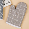 A pair of gray checkered heat-resistant kitchen oven gloves lying on a light background.