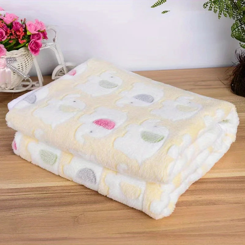 A stack of fluffy, multi-colored flannel pet blankets for dogs and cats on a wooden surface.