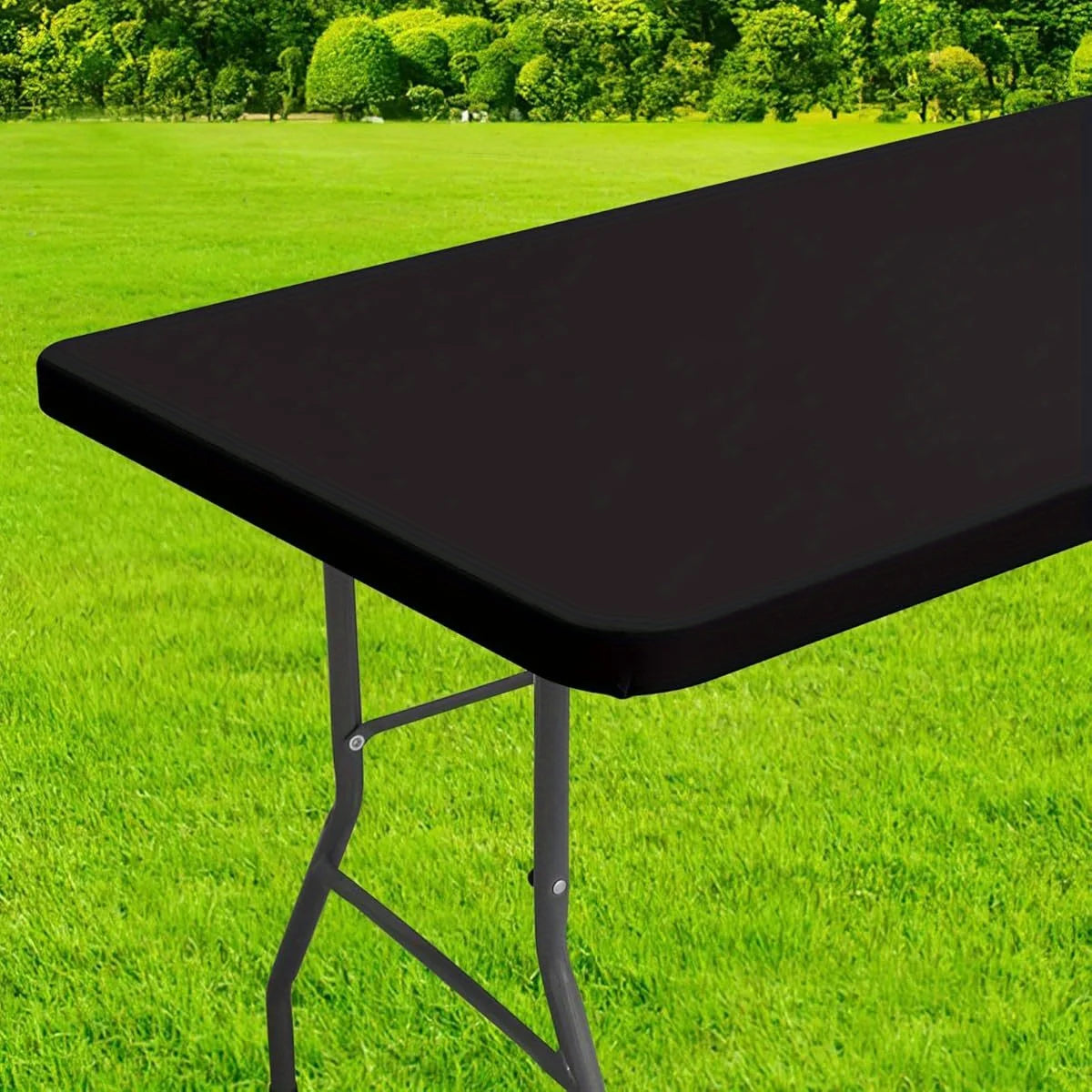A black waterproof rectangle tablecloth is shown on a folding table outdoors on green grass.
