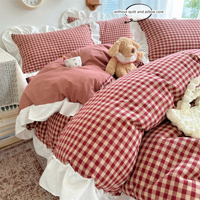 A plaid duvet cover set featuring red and cream checks with white lace embroidery on a bed.