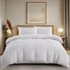 A white tufted microfiber duvet cover set displayed on a bed with a wooden headboard and framed artwork.
