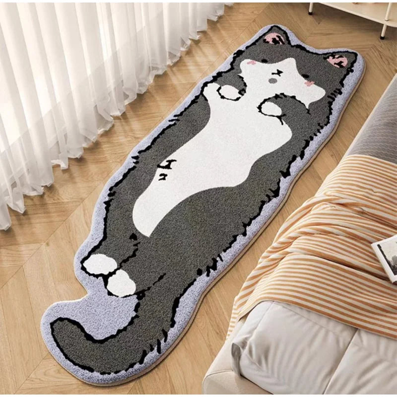 A decorative cat mat with a black and white cat design is placed on a wooden floor next to a bed.