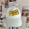 A white baseball cap with a yellow text patch embroidered on the front, featuring the phrase There is nothing basic about me.