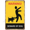 A vintage yellow warning sign with black text and silhouette of a dog, indicating beware of dog.