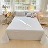 A white checkered flat sheet and pillow set is displayed on a bed in a bright room with large windows.