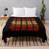 Black knitted throw blanket with colorful text reading FORTIES on a wooden surface.