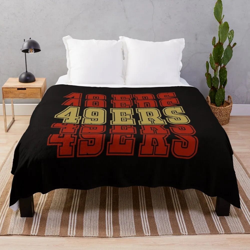 Black knitted throw blanket with colorful text reading FORTIES on a wooden surface.