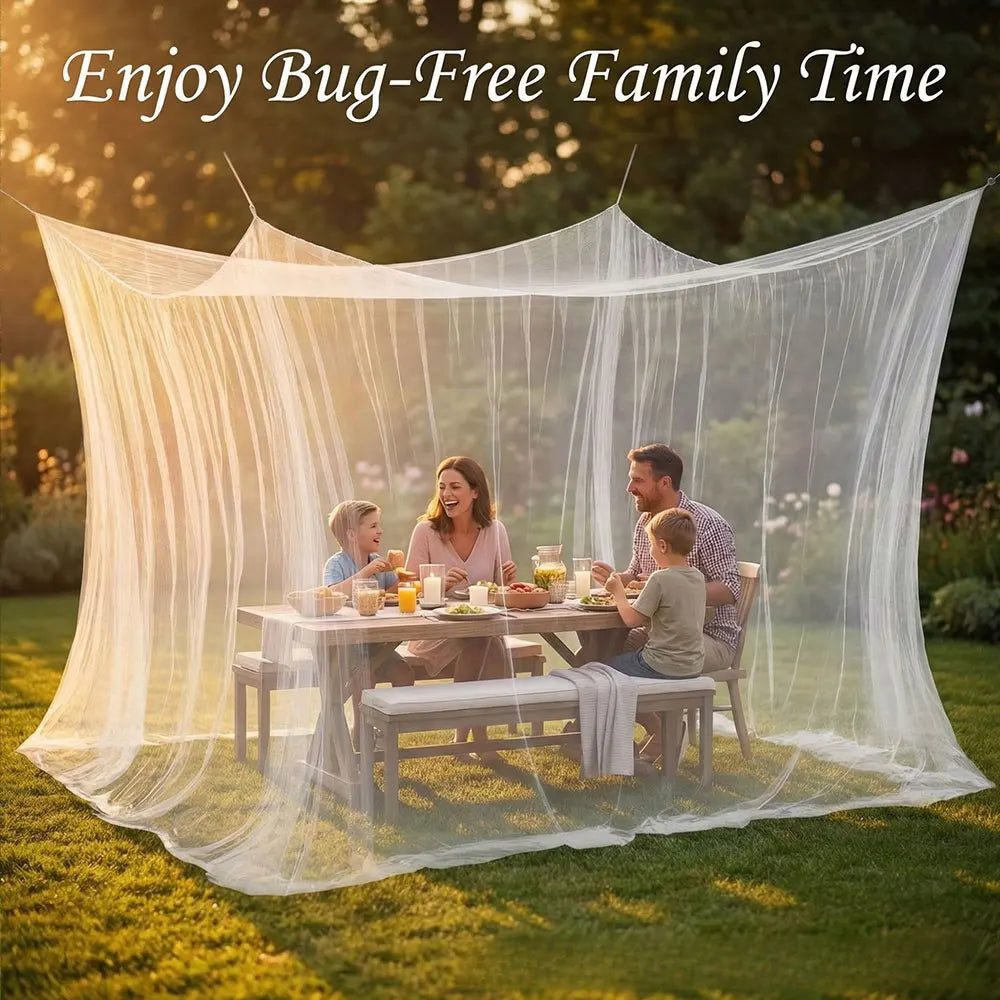 A family enjoying time under a large, sheer white mosquito netting canopy outdoors on a grassy lawn.