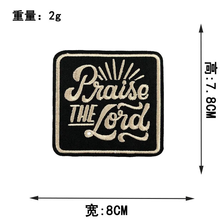 Black embroidered iron-on clothing patch with the text Praise The Lord in gold thread.