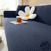 A dark blue textured sofa cover featuring a modern white decorative cushion on a light-colored rug.