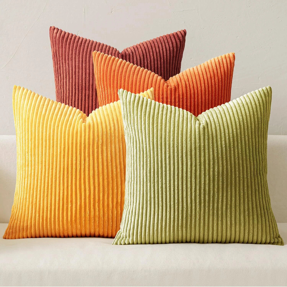 A set of four textured throw pillows in shades of orange, terracotta, and lime green.