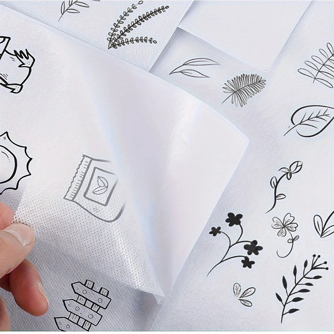 Close-up of water-soluble adhesive embroidery stabilizer sheets with various line drawings of leaves and floral elements.