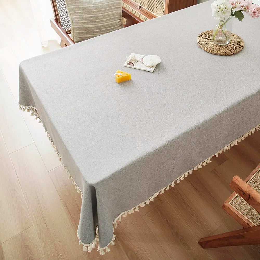 A light gray textured cotton table runner is displayed on a wooden table with a floral arrangement.