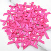 A pile of bright pink satin ribbon bows for crafts and decor scattered on a white marble surface.