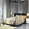 A bedroom featuring a bed draped with sheer mosquito net curtains and patterned bedding.