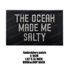 Black embroidered patch with white text that reads The Ocean Made Me Salty