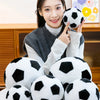 A woman holds a black and white football plush toy against a light background.