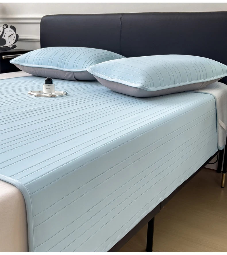 Light blue striped cooling ice silk bed pad placed on a bed with a dark headboard.