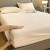 A hand gently touches a cream-colored duvet on a bed with white pillows.
