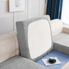 A close-up of a light gray waterproof jacquard stretch sofa cover with a white cushion on a beige sofa.
