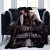 A dark brown horror themed throw blanket featuring a knife design draped over a dark sofa.