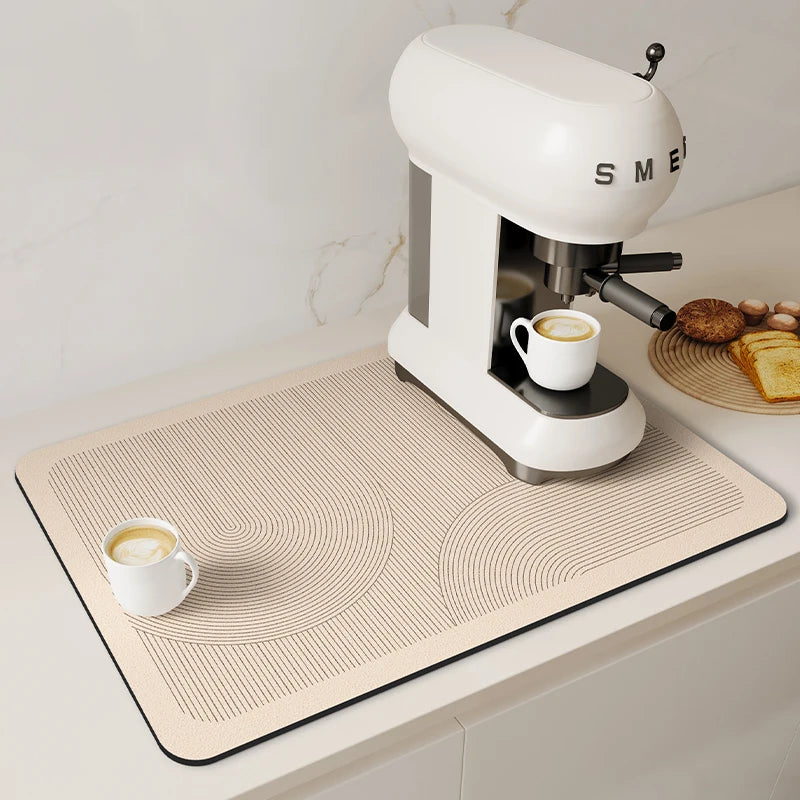 A white electric coffee grinder sits on a beige drain mat with concentric circles, next to a white cup of coffee.