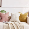 A collection of beige and pink boucle texture throw pillows resting on a light-colored sofa.