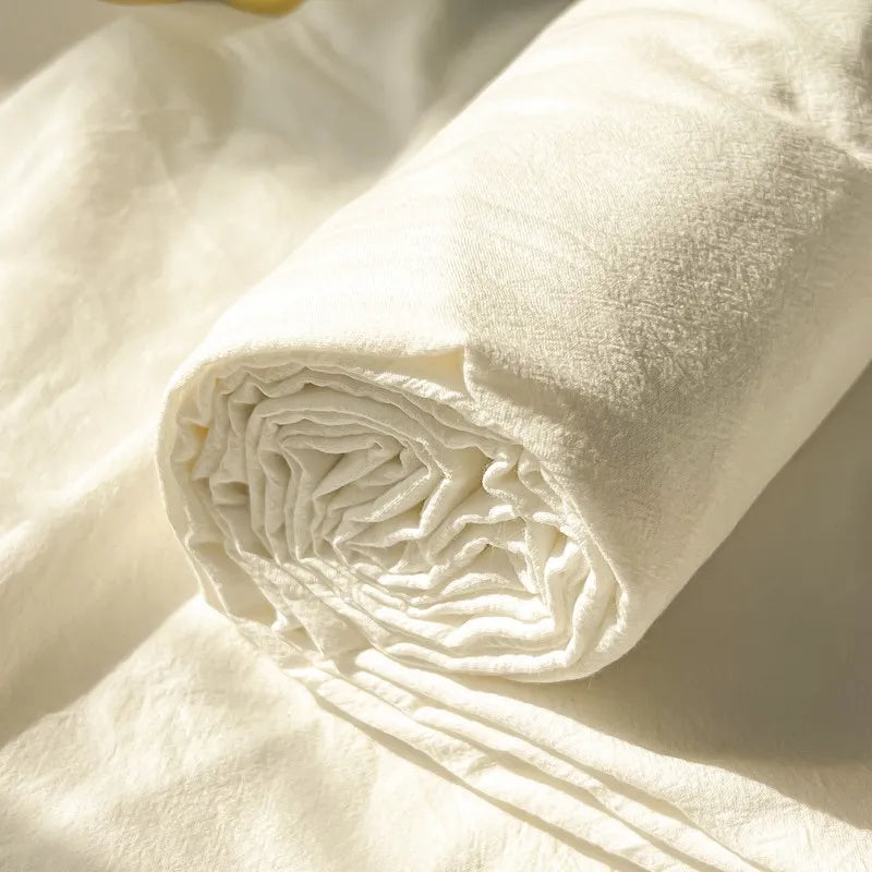 A rolled white organic cotton bedding set showing the texture of the fabric.