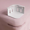 A white plastic clip product is shown against a pink background, demonstrating its use for securing fabric.