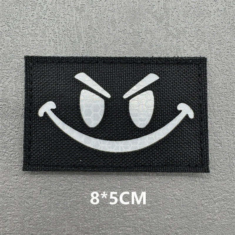 Black embroidered patch featuring a white angry face emoji design