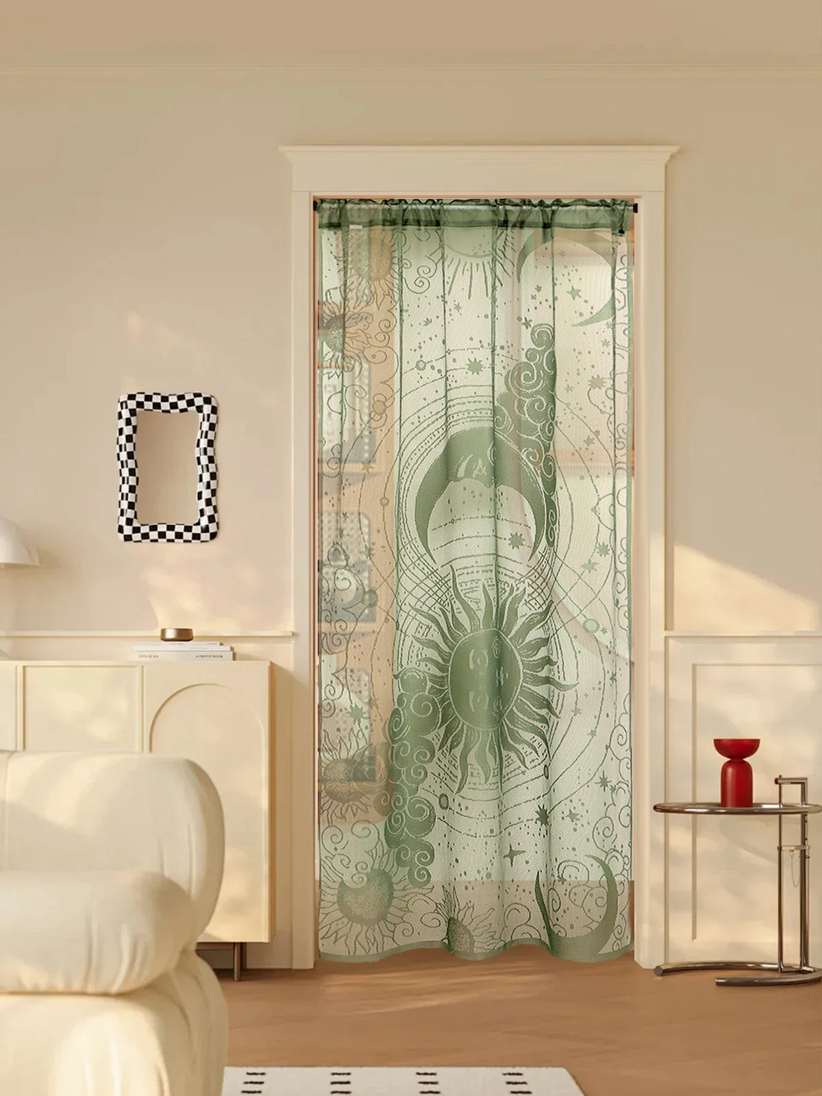 A sheer green lace door curtain featuring a sun and moon design hangs in a white frame.