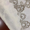 Close-up of a white tablecloth with elegant gray lace trim and floral embroidery.