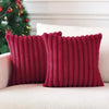 Two deep red plush striped decorative pillowcases resting on a white sofa.