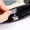 A hand is opening a black fabric bag to show two silver magnetic snap fasteners with blue electrical sparks.