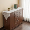 A wooden cabinet with a lace runner display featuring books and a potted plant.