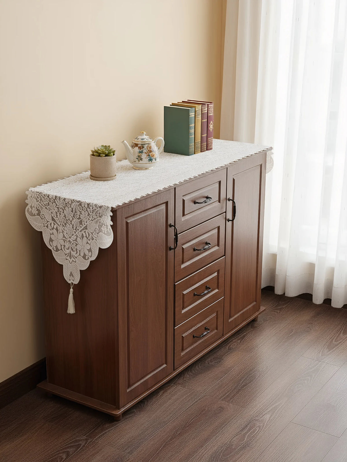 A wooden cabinet with a lace runner display featuring books and a potted plant.