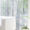 White beaded string curtains covering a window with a soft, sheer texture.