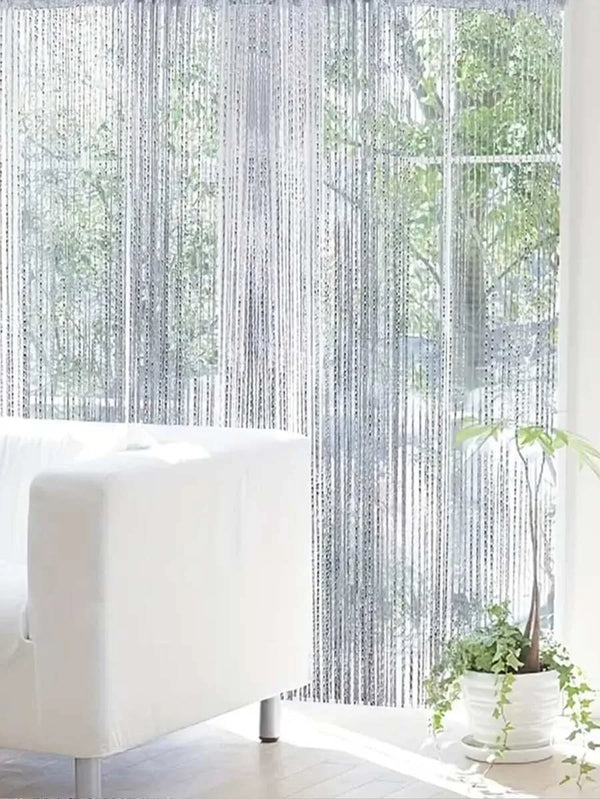 White beaded string curtains covering a window with a soft, sheer texture.