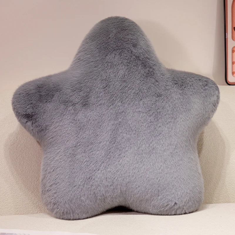 A soft gray star-shaped decorative throw pillow resting on a light surface.