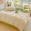 Floral printed bedding set featuring light pink and green patterns on a bed with sheer white blinds.