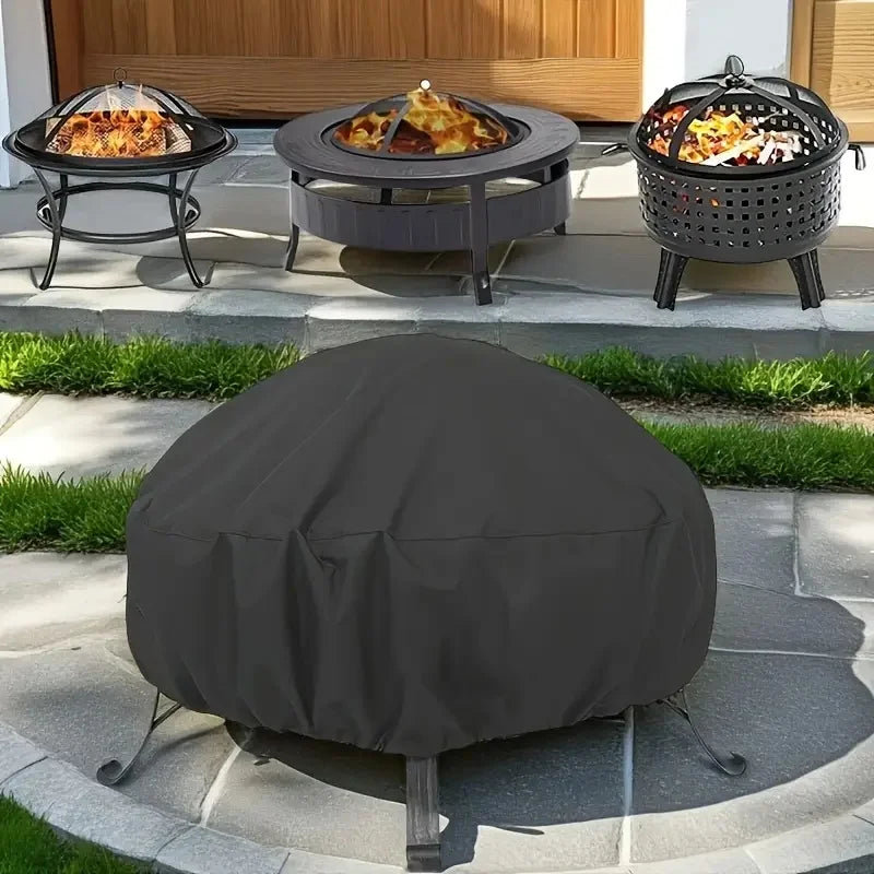 A black round fire pit cover is placed on a stone patio next to a grill and a fire pit table.