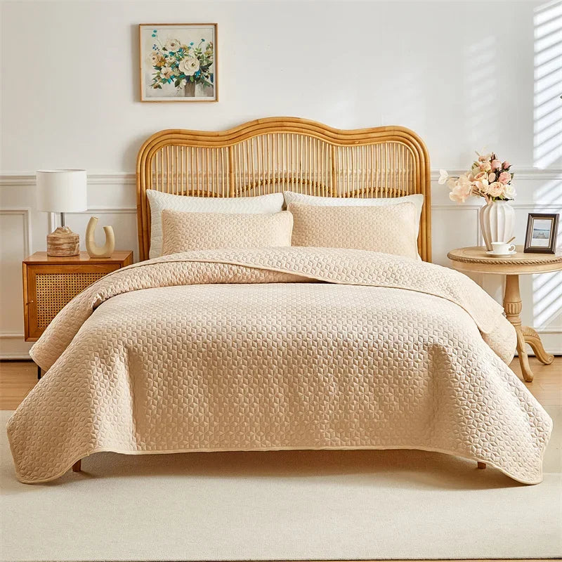 A beige plaid quilt set is displayed on a queen bed with a light wood headboard and white bedding.