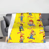 A yellow flannel throw blanket featuring illustrations of Good Guys from the Chucky horror movie.