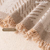 Close-up of a beige woven textile featuring handmade woven tassels and a fishbone pattern.