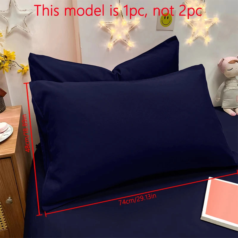 A dark navy blue matte solid color pillowcase displayed on a bed with decorative star lights.