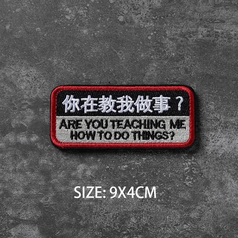 A black and red embroidered badge with Chinese and English text on a dark gray textured background.