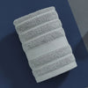A stack of four white, textured cotton face towels arranged in a diagonal pattern.