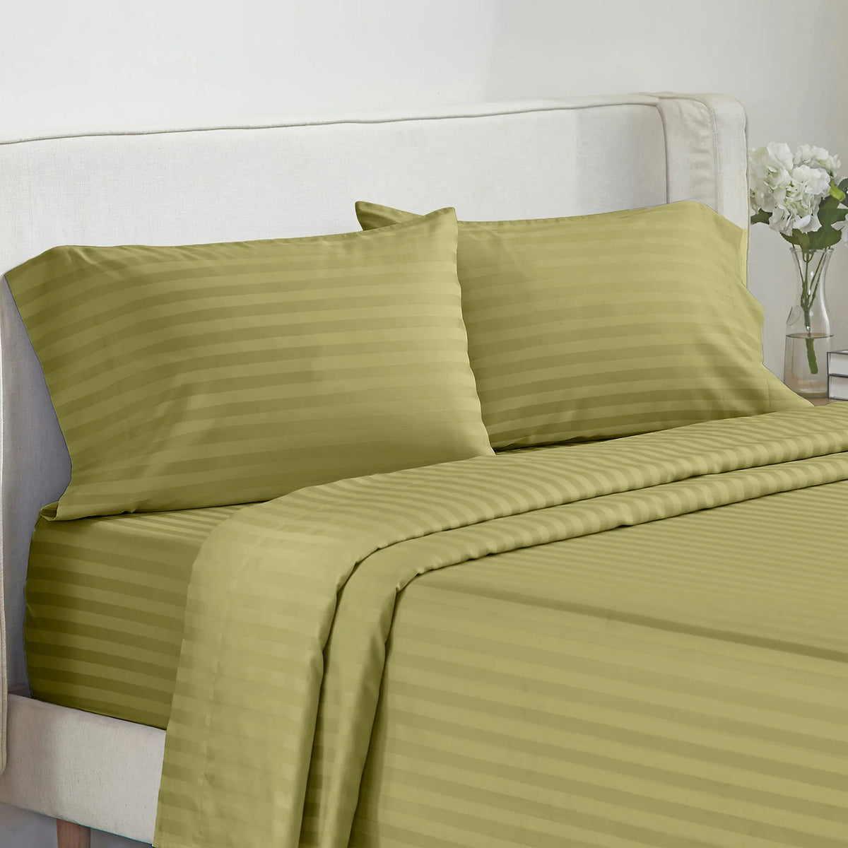 A set of olive green striped bedding, including pillows and a duvet cover, on a white bed.