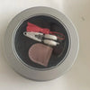 Mini precision sewing scissors with a protective cover and red thread inside a silver container.